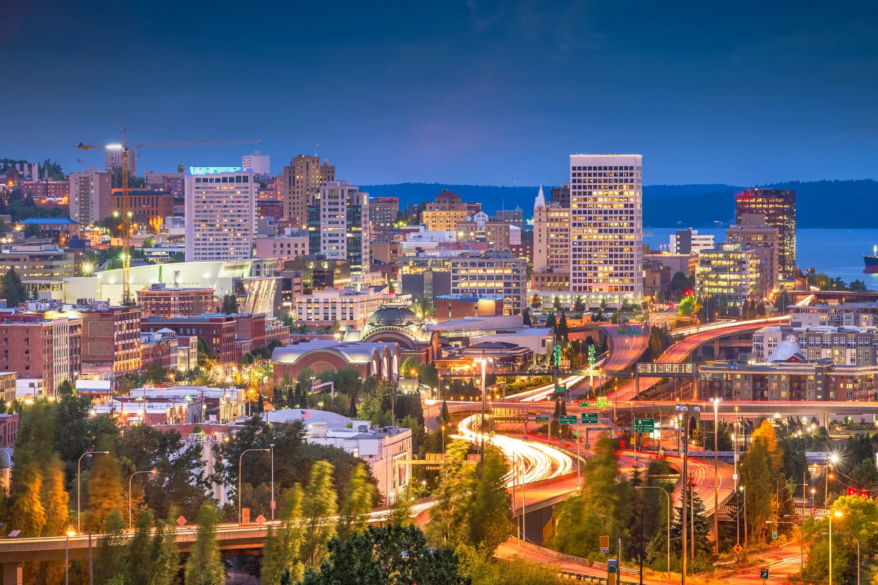 Downtown Tacoma Washington at dusk, lots of large buildings and twisting streets, water in the distance