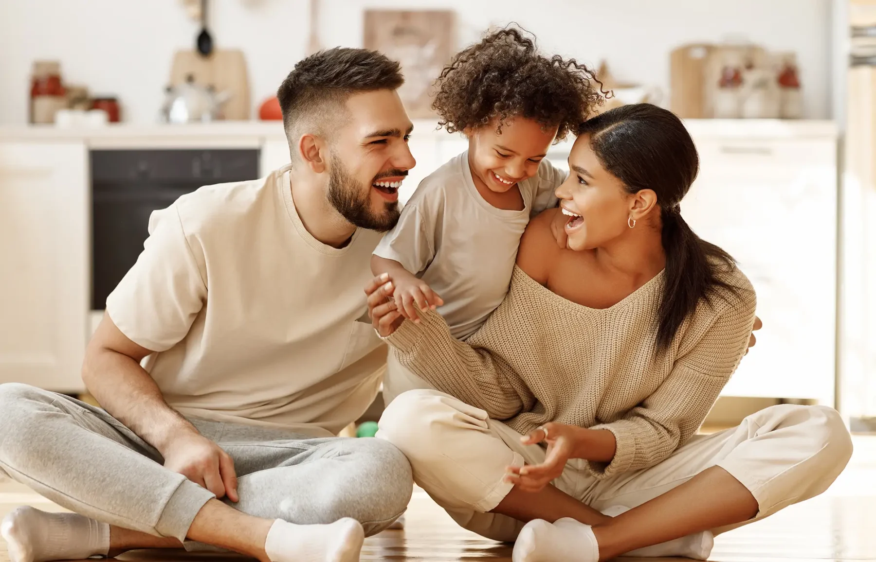 Young couple with child sitting on the floor laughing