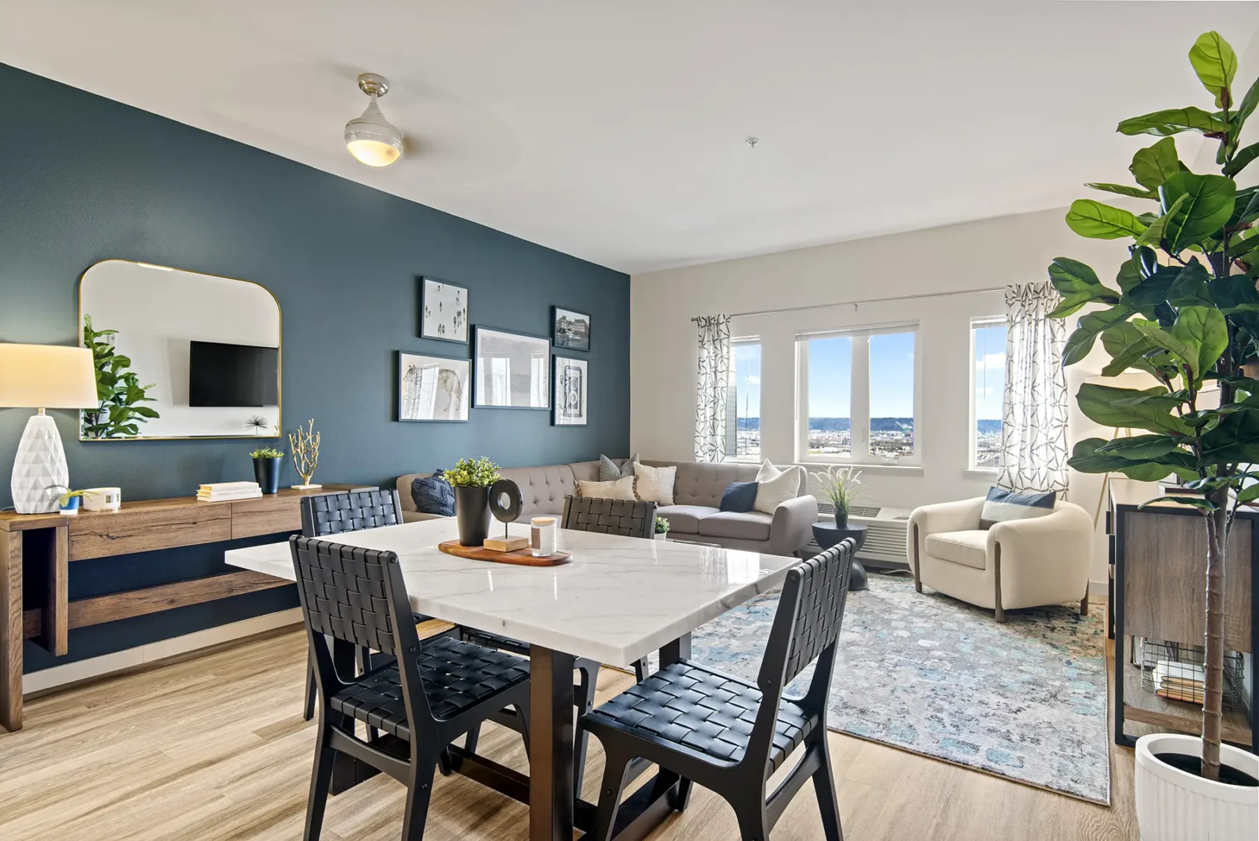 Staged dining and living room with blue accent wall and large windows
